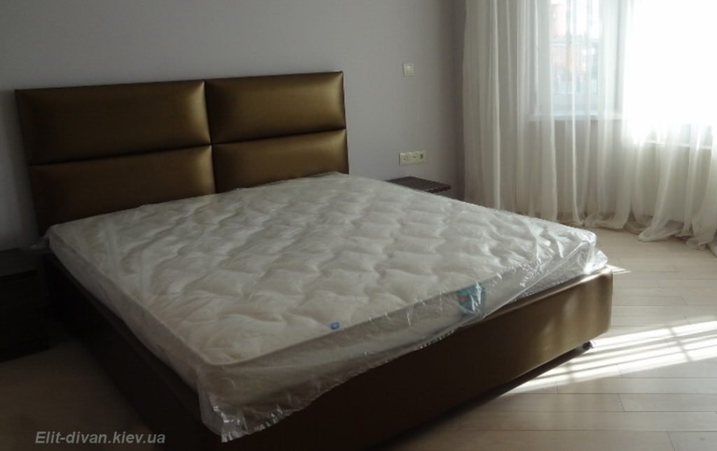 коричневая кровать с мягким изголовьем